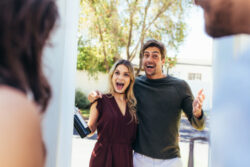 Excited,Couple,At,Entrance,Door,With,Bottle,Of,Wine.,Friends