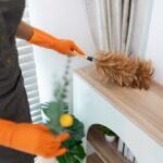 Professional,Housekeeper,Dusting,A,Shelf,With,Feather,Duster,In,A