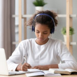 Focused,African,American,Teenage,Girl,Wearing,Headphones,Writing,Notes,Study